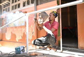 Welder, Peter Simpson, adds the finishing touches to a railing to support ramp access at Park Mountain Primary and Infant School in St. Elizabeth during Labour Day activities at the institution, which was the Parish Project, on Thursday (May 23).