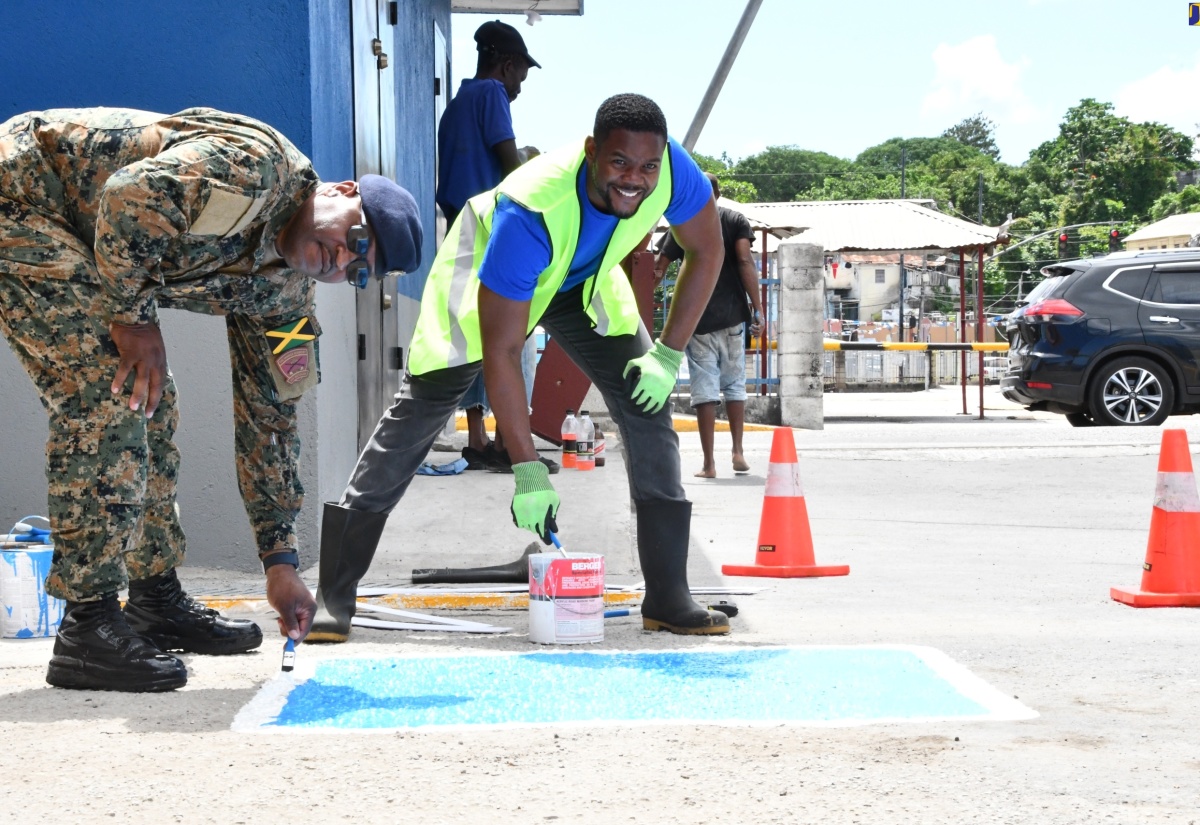 Mayor of Montego Bay and Chairman of the St. James Municipal Corporation, Councillor Richard Vernon (right), and Commanding Officer for the second battalion, Jamaica Regiment, Jamaica Defence Force, Lieutenant Colonel Anthony Lysight, paint disabled parking spaces at a car park at the intersection of Creek Street and St. Clavers Avenue in Montego Bay. The work was part of the Labour Day parish project on Thursday (May 23).