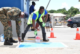 Mayor of Montego Bay and Chairman of the St. James Municipal Corporation, Councillor Richard Vernon (right), and Commanding Officer for the second battalion, Jamaica Regiment, Jamaica Defence Force, Lieutenant Colonel Anthony Lysight, paint disabled parking spaces at a car park at the intersection of Creek Street and St. Clavers Avenue in Montego Bay. The work was part of the Labour Day parish project on Thursday (May 23).