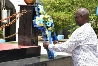 Minister of Local Government and Community Development, Hon. Desmond McKenzie, places a floral tribute at the Secret Gardens monument, which bears the names of children, who have lost their lives under tragic and violent circumstances. Occasion was the Kingston and St. Andrew Municipal Corporation’s  (KSAMC) Child Month ceremony held at the monument, downtown Kingston on Sunday (May 5).