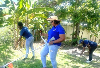 Team members of the Hanover Parish Court join forces with members of the Jamaica Constabulary Force (JCF) in cleaning the courtyard on Labour Day, Thursday, May 23.