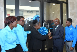 Minister of Culture, Gender, Entertainment and Sport, and Member of Parliament for St. Catherine Central, Hon. Olivia Grange (centre) and Industry, Investment and Commerce Minister, Senator the Hon. Aubyn Hill (second right), cut the ribbon to open the new R.A. Williams Distributors Limited facility in the New Brunswick Village in St. Catherine, recently. Observing (from left) are Chief Operations Officer, R.A. Williams Distributors Limited, Jewel Reid; Founder and Chief Quality Officer, Evelyn Williams; and Chief Executive Officer, Audley Reid.


