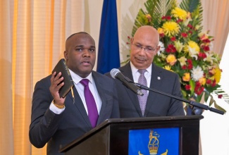 Governor-General His Excellency the Most Hon. Sir Patrick Allen  (right) listens as newly appointed Parliamentary Secretary, Senator Abka Fitz-Henley (centre) takes the Oath of Allegiance and the Oath of Office during the swearing-in ceremony held at King’s House on May 22.