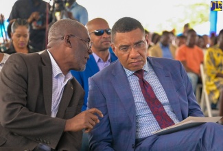 Prime Minister, the Most Hon. Andrew Holness (right), converses with National Housing Trust (NHT) Chairman, Linval Freeman, during the official handover of residential serviced lots under the new Friendship Oaks Phase 1 development in Goshen, St. Elizabeth, on May 17.
