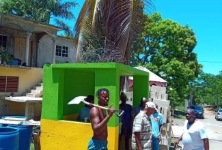 Volunteers from the Exchange District in St. Ann paint the bus stop in Jamaican colours on Labour Day, May 23.

