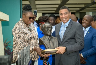 Prime Minister, the Most Hon. Andrew Holness (right), and Minister of Culture, Gender, Entertainment and Sport, Hon. Olivia Grange, hold a replica of the Lynden G. Newland bust. Occasion was the unveiling for the sculpture in honour of the late former Labour Minister, at the Ministry of Labour and Social Security’s National Heroes Circle location in Kingston on May 22. Sharing the moment is Labour and Social Security Minister, Hon. Pearnel Charles Jr.

