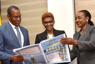 Minister of Finance and the Public Service (MoFPS), Dr. the Hon. Nigel Clarke (left); State Minister, Ministry of Education and Youth, Hon. Marsha Smith (right); and Deputy Financial Secretary, Public Expenditure Division, MoFPS, Loris Jarrett, view the MoFPS’ Citizens’ Guide to the 2024/25 Budget, which will be distributed to schools island wide.  Copies of the guide were handed over to the Education Ministry , during a ceremony held at the Finance Ministry’s National Heroes Circle offices in Kingston on Friday (May 3).