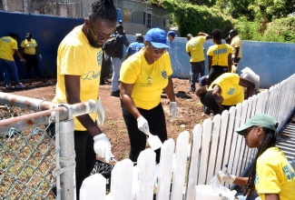 HEART/NSTA Trust volunteers paint a picket fence at Stimulation Plus Child Development Centre on Ostend Close in Kingston on Labour Day (May 23).

