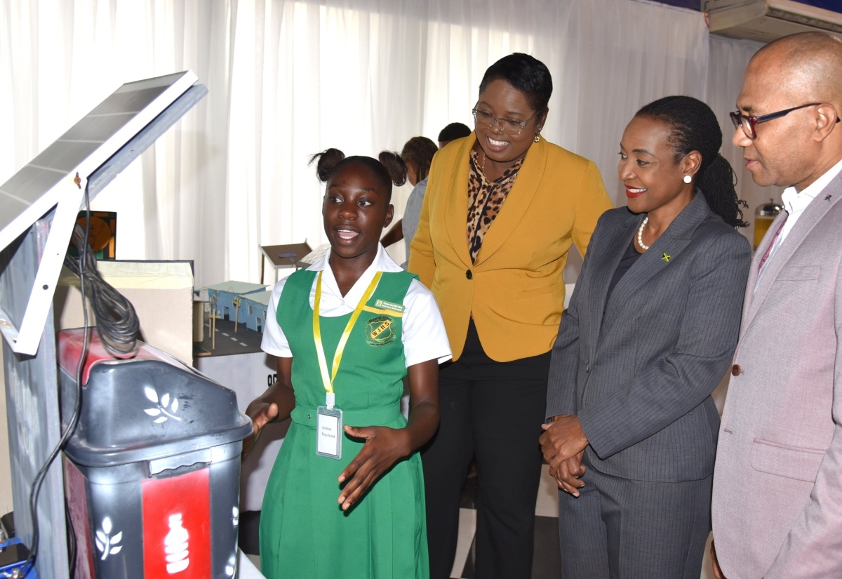 Minister of State in the Ministry of Education and Youth, Hon. Marsha Smith (second right), listens as 17-year-old Winston Jones High School student, Jodean Raymond (left), explains how her 'Wimmie Joe Smart Bin’ functions, at the British Council Caribbean STEAM Innovation Challenge closing ceremony held on Friday (May 3), at the Terra Nova All-Suite Hotel in Kingston. Also listening are Chief Education Officer in the Ministry, Terry-Ann Thomas-Gayle; and Chief Executive Officer of eLearning Jamaica, Andrew Lee. 