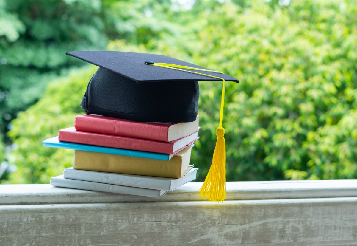 A graduation cap rests upon books, symbolizing the culmination of graduate studies. 