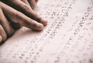 Cropped image of a person using braille to read. 