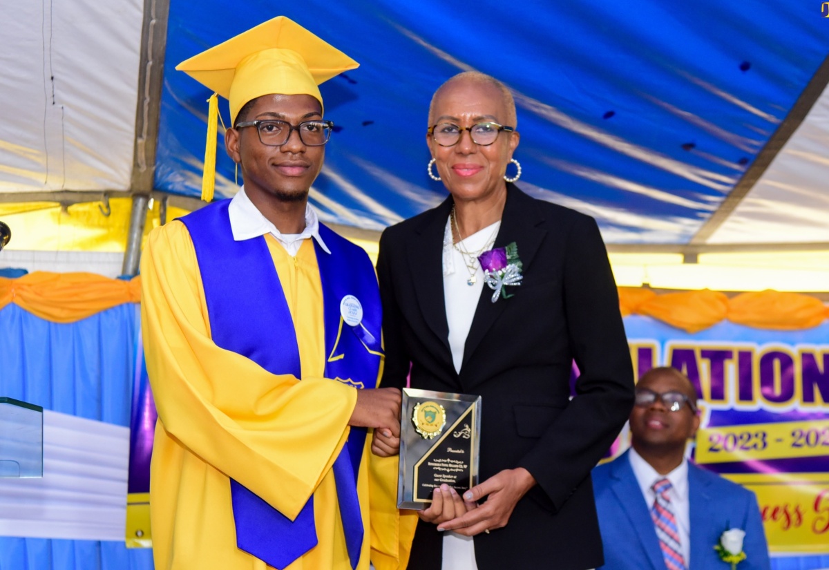 Minister of Education and Youth, Hon. Fayval Williams (right) is presented with a plaque of appreciation by student Marvin Blake (left) during the Guy’s Hill High School graduation ceremony held on the school campus in St. Catherine on Thursday (June 27).
