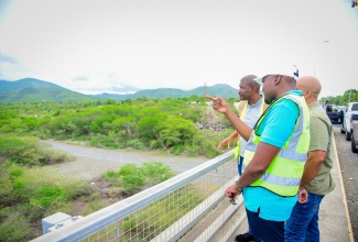 Minister without Portfolio in the Ministry of Economic Growth and Job Creation with Responsibility for Works, Hon. Robert Morgan (foreground), highlights aspects of work along a segment of the Southern Coastal Highway Improvement Project (SCHIP), between Harbour View, St. Andrew and Golden Grove, St. Thomas, to National Works Agency (NWA) Senior Director for Project Implementation, Varden Downer (left), and St. Thomas Western Member of Parliament, James Robertson, during a tour on Friday (June 7). 