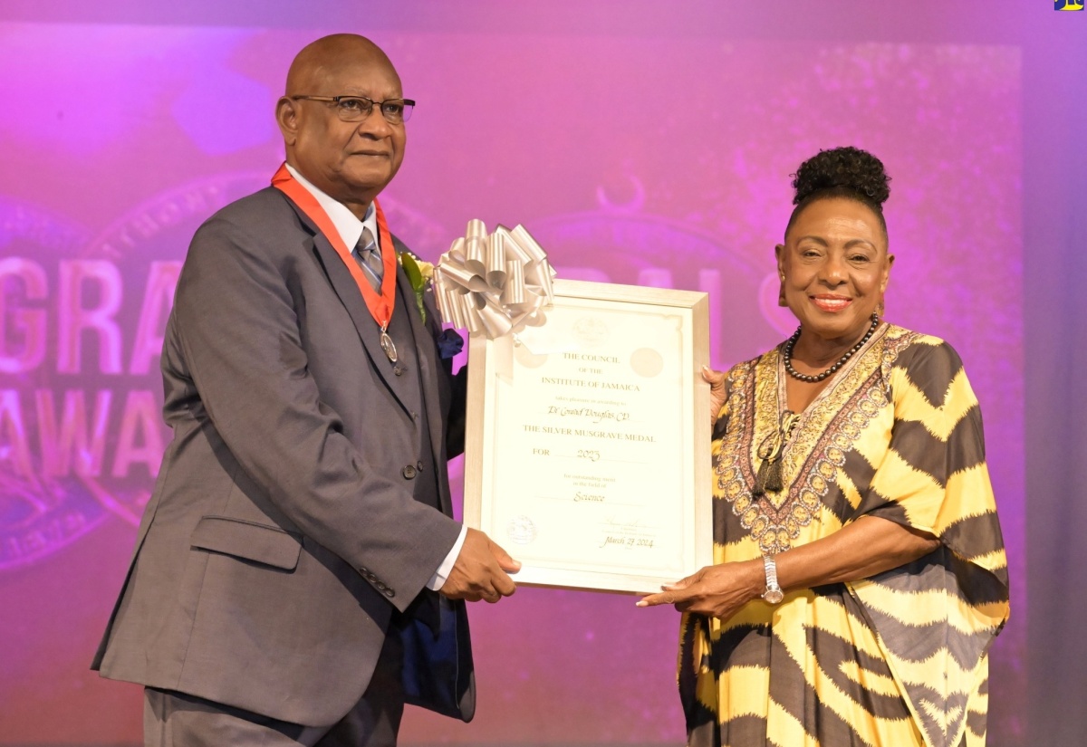 Minister of Culture, Gender, Entertainment and Sport, Hon. Olivia Grange (right) presents Dr. Conrad Douglas with the Silver Musgrave Medal for his work in Applied Science, Technology and Innovation in Industry and the Environment, during the awards ceremony at the Philip Sherlock Centre for the Creative Arts recently.