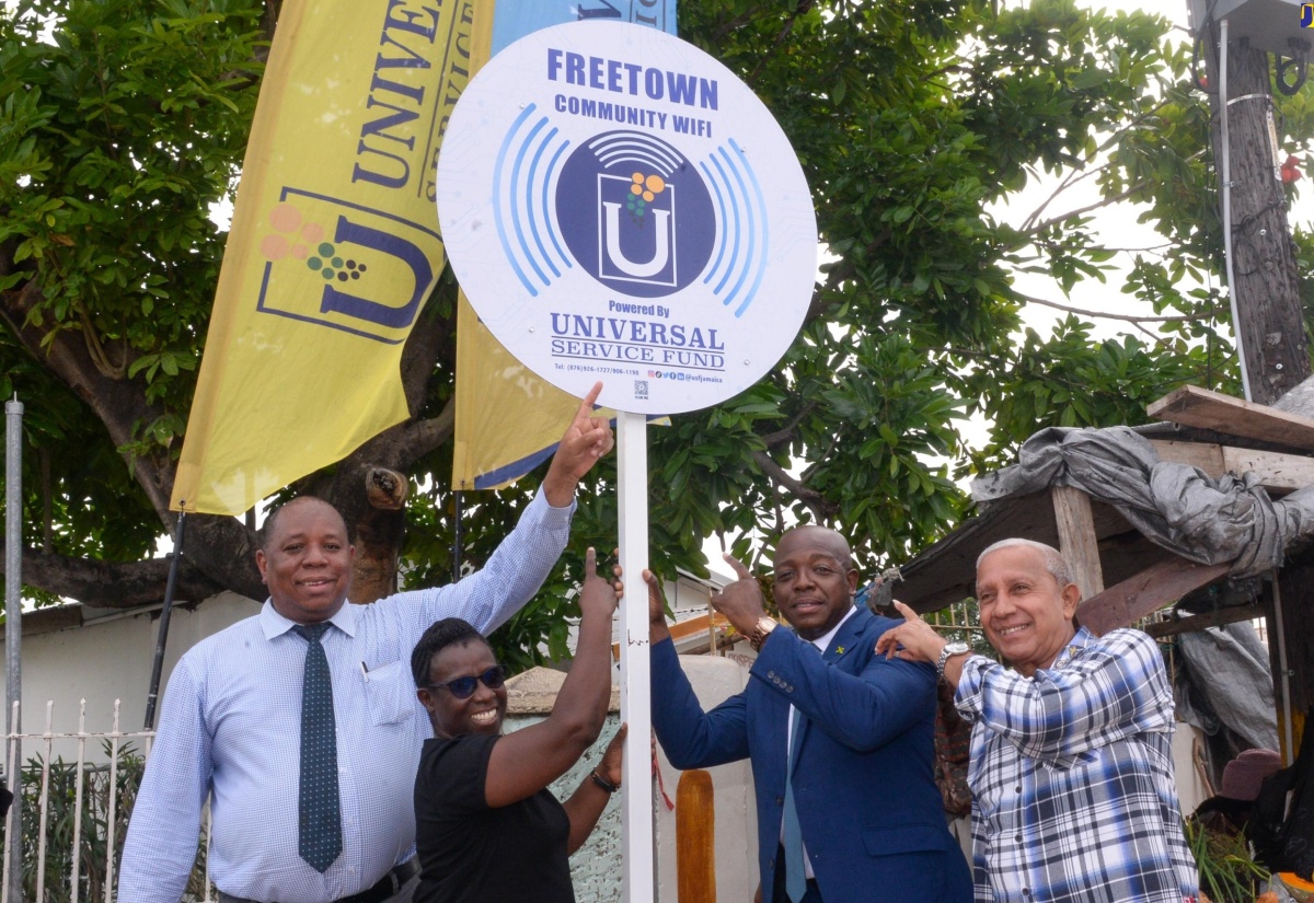 Minister of Labour and Social Security, Hon. Pearnel Charles Jr. (second right), points to a sign that was unveiled following the commissioning of community Wi-Fi service on Friday (June 7) in Freetown, Clarendon South Eastern, for which he is the Member of Parliament. The service was installed by the Universal Service Fund (USF). Sharing the moment are (from left) USF Chief Executive Officer (Acting), Andrew McRae; and Clarendon Municipal Corporation Councillors for the Palmers Cross Division, Carlene Benjamin, and Rocky Point Division, Winston Maragh. The USF is an agency of the Ministry of Science, Energy, Telecommunications and Transport, mandated to ensure access to information and communications technology tools to facilitate development.