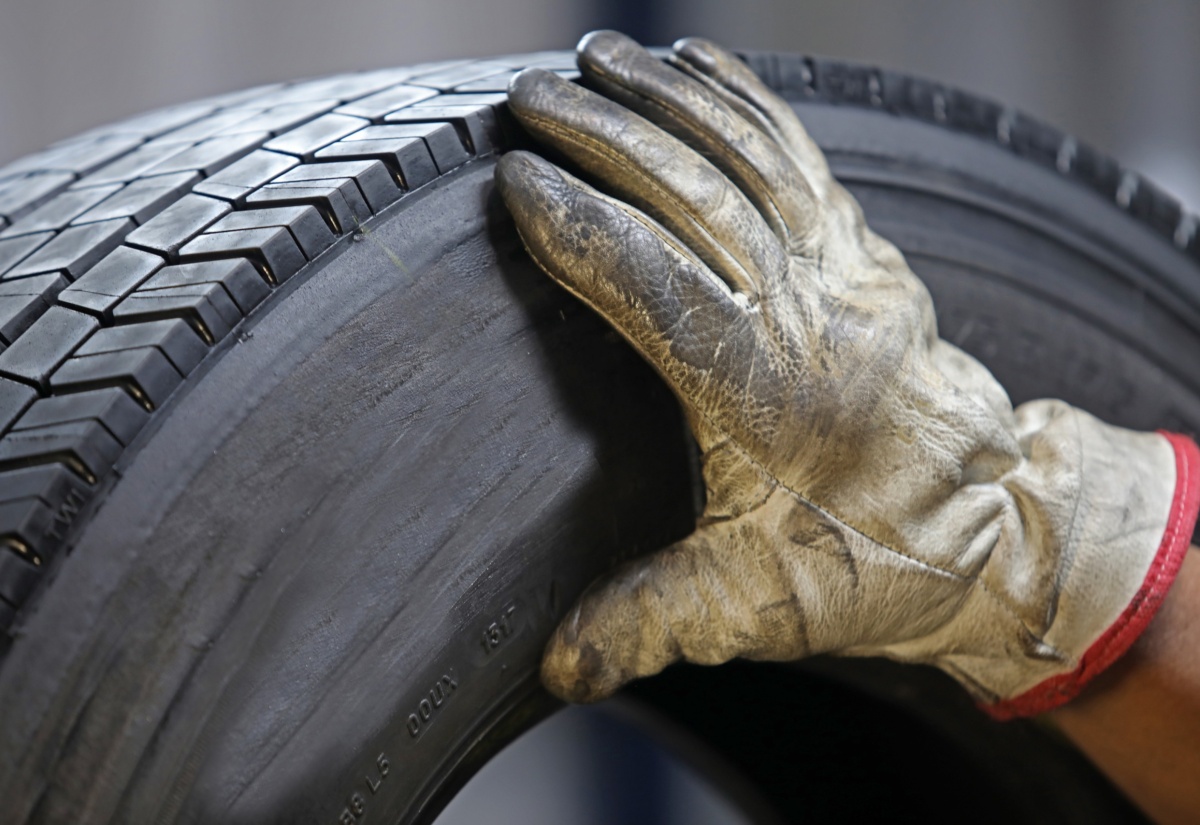 A person wearing an industry glove touches a retreaded tyre. 