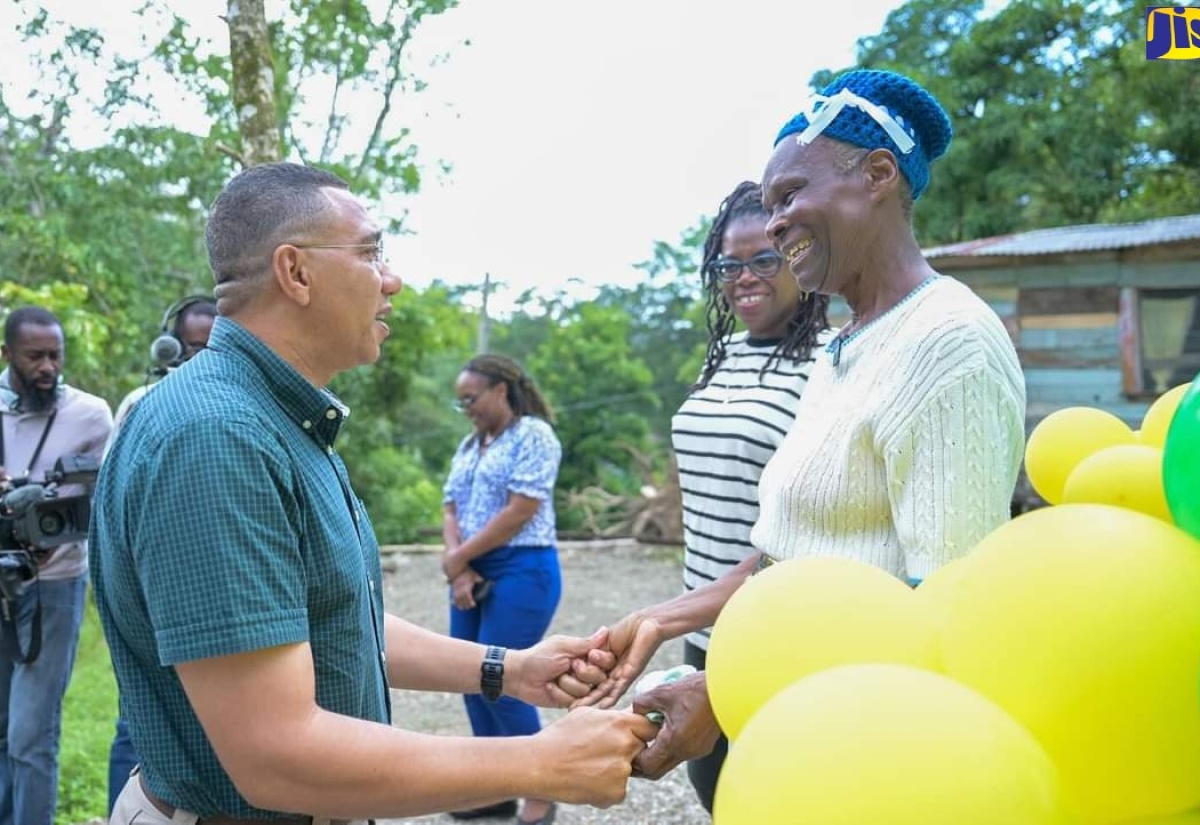 Prime Minister, the Most Hon. Andrew Holness (left), greets New Housing Social Programme (NHSP) beneficiary, Enid Chisholm (right), on arrival in Baulk District, Hanover on July 12. Looking on is Member of Parliament for Western Hanover, Tamika Davis.

