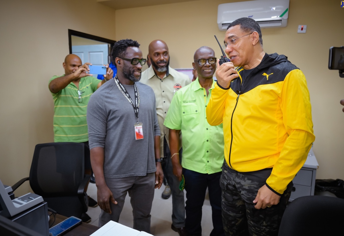 Prime Minister, the Most Hon. Andrew Holness (right), uses a two-way radio, which is part of the Disaster Emergency Communication System during a visit to the National Emergency Operations Centre, located at the Office of Disaster Preparedness and Emergency Management (ODPEM) in Kingston on Wednesday (July 3). Others (from left) are: Project Engineer at the Japan International Co-operation Agency (JICA), Dane Lawrence; Acting Director General, ODPEM, Richard Thompson, and Minister of Local Government and Community Development, Hon. Desmond McKenzie.

