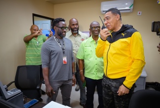 Prime Minister, the Most Hon. Andrew Holness (right), uses a two-day radio, which is part of the Disaster Emergency Communication System during a visit to the National Emergency Operations Centre, located at the Office of Disaster Preparedness and Emergency Management (ODPEM) in Kingston on Wednesday (July 3). Others (from left) are: Project Engineer at the Japan International Co-operation Agency (JICA), Dane Lawrence; Acting Director General, ODPEM, Richard Thompson, and Minister of Local Government and Community Development, Hon. Desmond McKenzie.

