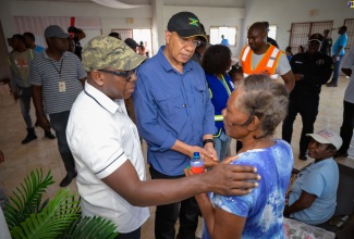 Prime Minister, the Most Hon. Andrew Holness (centre) and Minister of Labour and Social Security, Hon. Pearnel Charles Jr., comfort a resident of Rocky Point in Clarendon, during a visit to the area on Saturday (July 6), to assess damage from Hurricane Beryl.