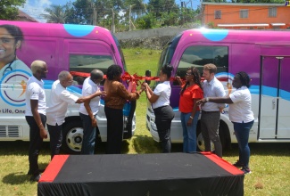Associate Director, Meeting Targets and Maintaining Epidemic Control (EpiC), Sue-Ann Wallace-Brown (fourth left) and Project Coordinator (left), Jamaica Aids Support for Life (JASL) Nicola Sybliss McLeod (fourth right), cut the ribbon to officially hand over two mobile health units under the ‘One Life, One Health’ project. Occasion was the launch of the project and the staging of a mobile health clinic in Lodge, St. Ann, on Friday (July 12). Sharing the moment (from left) are St. James Regional Programme Manager, JASL, Desmond Campbell; Board Member, JASL, Gervaise McLeod; Medical Director, JASL, Dr. Jennifer Brown Tomlinson; Project Management Specialist, United States Agency for International Development (USAID), Althea Spence; Foreign Service Officer, USAID, Jermey Taglieri; and St. Ann Regional Programme Manager, JASL, Nilfia Hazel Anderson.