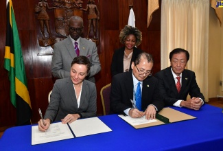 Minister of Foreign Affairs and Foreign Trade, Senator the Hon. Kamina Johnson Smith (seated, left) and Resident Representative of the Japan International Cooperation Agency (JICA), Mitsuyoshi Kawasaki (seated, centre), sign a memorandum of understanding (MOU) during the handover of emergency relief items from the Government of Japan, at Jamaica House on July 15. Looking on are Minister of Local Government and Community Development, Hon. Desmond McKenzie (standing, left); Minister without Portfolio in the Office of the Prime Minister with Oversight for Skills, Digital Transformation and Information, Senator Dr. the Hon. Dana Morris-Dixon (standing left); and Japanese Ambassador, His Excellency Yasuhiro Atsumi. The donation comes after the Category 4 Hurricane Beryl impacted Jamaica on July 3.

