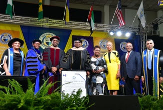 Minister of Tourism, Hon. Edmund Bartlett (fourth left), who received an Honorary Doctorate in Hospitality and Tourism Management from the University of the Commonwealth Caribbean (UCC), at a graduation ceremony, held at the National Arena, on Sunday (July 28), shares a  photo opportunity with (from left) Deputy Group Executive Chairperson of the University of the Commonwealth Caribbean (UCC), Geraldine Adams; President of the UCC, Professor Colin Gyles; Group Executive Chairman of UCC, Dr. Winston Adams; Minister of Culture, Gender, Entertainment and Sport, Hon. Olivia Grange; Minister of Education and Youth, Hon. Fayval Williams; Minister of Industry, Investment and Commerce, Senator the Hon. Aubyn Hill, and President of Strategic Holdings Group, His Excellency Dawood Al Shezawi.

