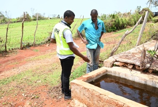 Entomological Assistant, Charles Killingbeck (left), points to an untreated water source on the property of Howard Gayle of Pedro Plains, during a Southern Regional Health Authority (SRHA) mass public health intervention in St. Elizabeth, on Wednesday, July 10.

