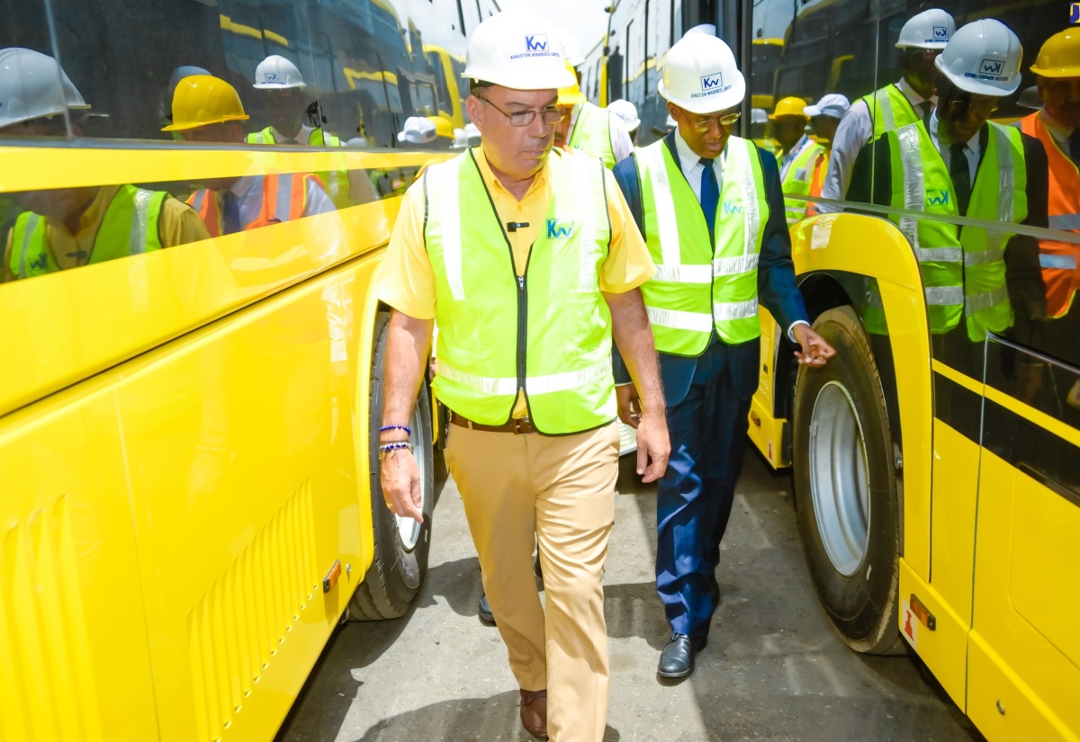 Minister of Science, Energy, Telecommunications and Transport, Hon. Daryl Vaz (left), and Minister of Finance and the Public Service, Dr. the Hon. Nigel Clarke, look at some of the 100 new Jamaica Urban Transit Company Limited (JUTC) buses, which arrived in the island on Monday (July 15) at Kingston Wharves. The units were transported to the Portmore Depot after being cleared.