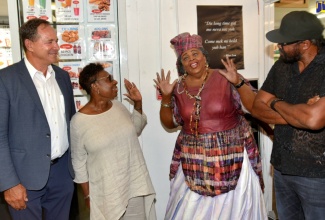 Minister of Culture, Gender, Entertainment and Sport, Hon. Olivia Grange (second left), looks at the life-size replica of cultural icon, Hon. Louise Bennett Coverley at the grand opening of S Foods Supermarket on Worthington Avenue, St. Andrew on Saturday (July 27).  Looking on are Chief Executive Officer of S Foods, Christopher Issa (left); and veteran Reggae artiste, Tony Rebel.