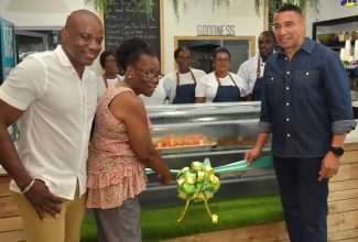 Prime Minister, the Most Hon. Andrew Holness (right), assists Averil Smith to cut the ribbon to officially open the Wholesome Café at the Digicel Food Court, downtown Kingston, on Sunday (July 28). Looking on is Chief Executive Officer, Wholesome Café, Elon Parkinson, son of Ms. Smith.


