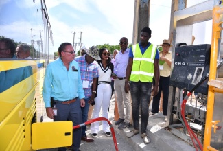 Minister of Science, Energy, Telecommunications and Transport, Hon. Daryl Vaz (left), looks on as a new Jamaica Urban Transit Company (JUTC) unit is being fueled at the New Fortress Energy Compressed Natural Gas (CNG) fueling station in Portmore St. Catherine, during a tour of the facility on Tuesday (July 30). He is accompanied by (from second left) Chairman of the Transport Authority, Owen Ellington; Vice President, New Fortress Energy, Verona Carter; Terminal Manager, New Fortress Energy, Robert Rodney; and Store Manager, Tevin Sinclair. The station has been expanded to accommodate the gassing of the 100 CNG buses that have been added to the JUTC fleet.