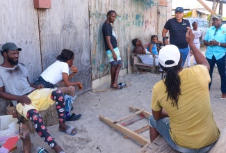 Minister of Health and Wellness, Dr. the Hon. Christopher Tufton (second right, standing), and Member of Parliament for Clarendon South Eastern, Hon. Pearnel Charles Jr. (right), speak with residents of Rocky Point in Clarendon, on July 25.