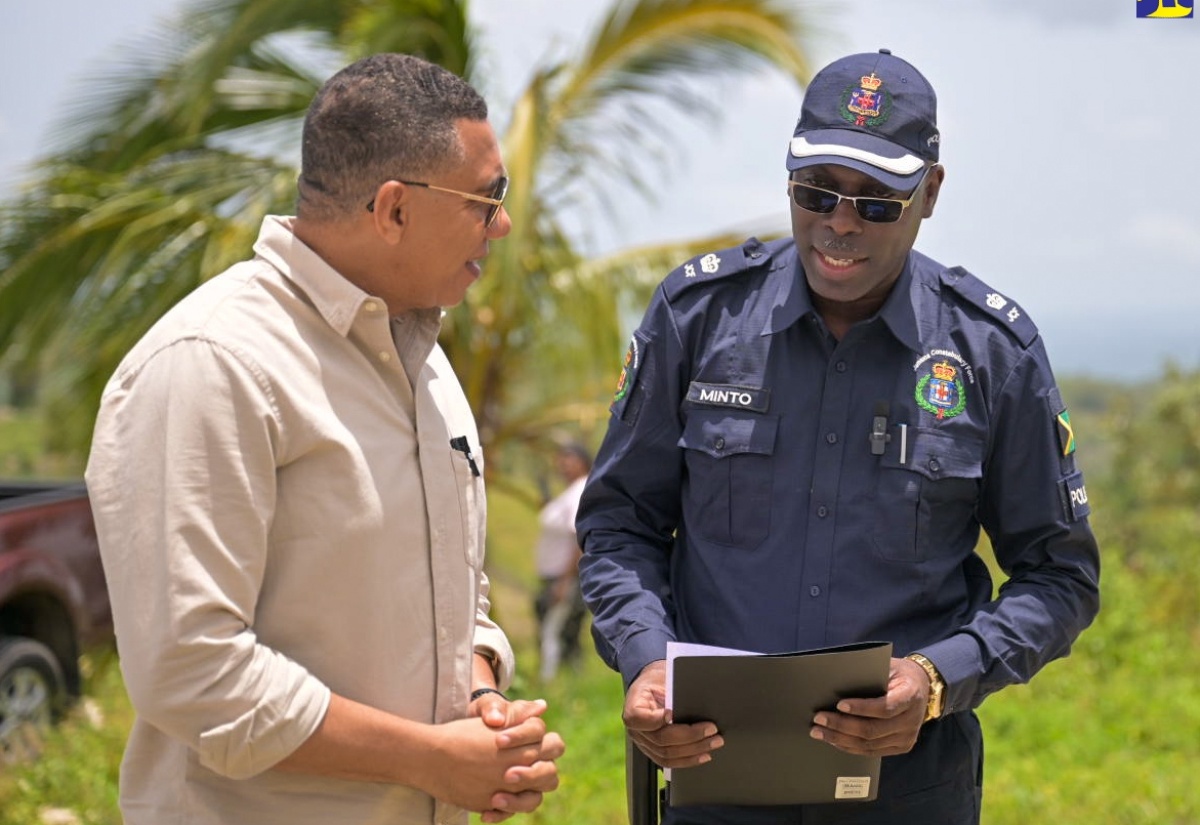 Prime Minister, the Most Hon. Andrew Holness (left), in discussion with Head of the St. Elizabeth Police Division, Superintendent Coleridge Minto, in Donegal district, St. Elizabeth, on Friday, July 19, during the handover of a housing unit under the New Social Housing Programme (NSHP).

