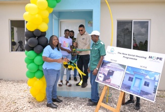 Prime Minister, the Most Hon. Andrew Holness (second right), is assisted by Yanique Duhaney (second left) of Donegal District in St. Elizabeth, in cutting the ribbon during the handover of her new home, built under the New Social Housing Programme (NSHP), on Friday (July 19). Looking on are Minister of State in the Ministry of Science, Energy, Telecommunications and Transport and Member of Parliament for St. Elizabeth North Western, Hon. William James Charles (J.C.) Hutchinson (right); Mayor of Black River and Chairman of the St. Elizabeth Municipal Corporation, Councillor Richard Solomon (centre); and Chair, NSHP Oversight Committee, Judith Robb Walters.