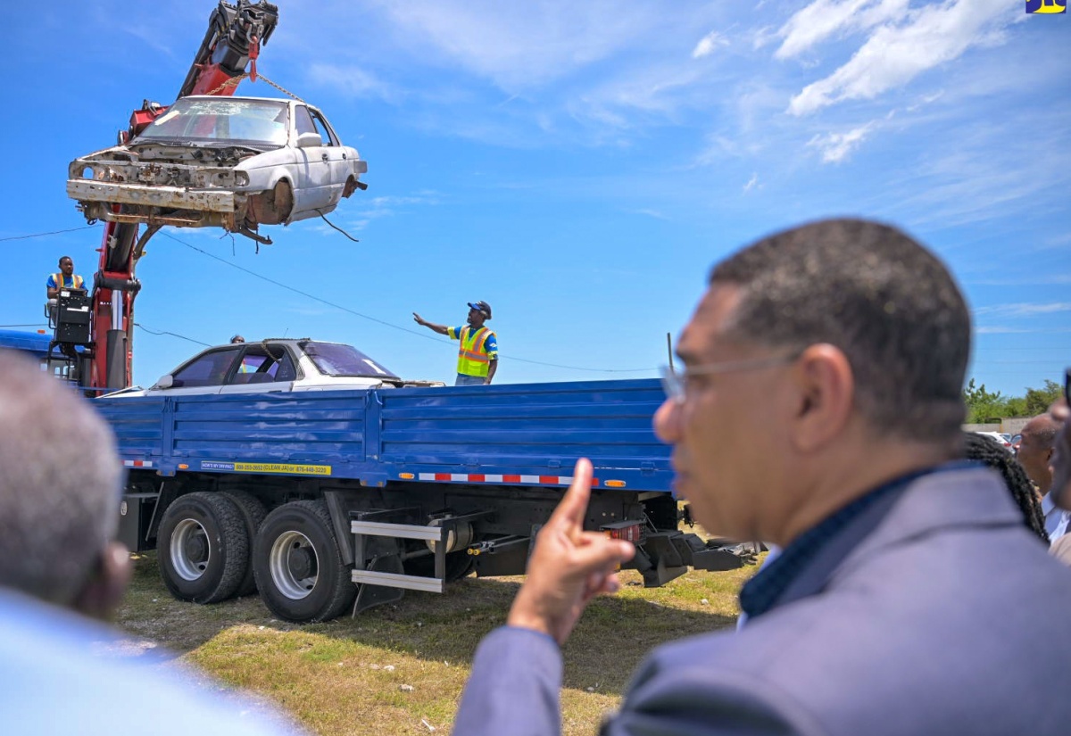 Prime Minister, the Most Hon. Andrew Holness, observes as workers from the National Solid Waste Management Authority (NSWMA) remove old motorcars under the Derelict Vehicles and Bulky Waste Removal programme. The post-Hurricane Beryl national clean-up exercise was officially launched on July 24 at the Waterford Community Centre in Portmore, St. Catherine.

