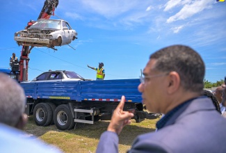 Prime Minister, the Most Hon. Andrew Holness, observes as workers from the National Solid Waste Management Authority (NSWMA) remove old motorcars under the Derelict Vehicles and Bulky Waste Removal programme. The post-Hurricane Beryl national clean-up exercise was officially launched on July 24 at the Waterford Community Centre in Portmore, St. Catherine.

