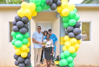 Prime Minister, the Most Hon. Andrew Holness (left), presents New Social Housing Programme (NSHP) beneficiary, Leta Williams, with the keys to her new two-bedroom home in Lodgie Green District in Grantham, Clarendon  on Friday (July 26). Sharing the moment are Member of Parliament for Clarendon North Western, Phillip Henriques, and NSHP officials. 