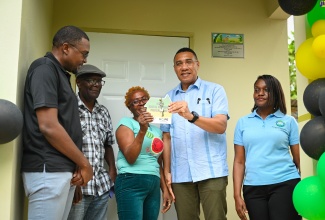 Prime Minister, the Most Hon. Andrew Holness (second right), presents the keys to a brand-new one-bedroom unit under the New Social Housing Programme (NSHP) to Beverly Howell (centre) in Clarendon North Central on August 2. Sharing in moment are (from left) Minister without Portfolio in the Ministry of Economic Growth and Job Creation and Member of Parliament for the constituency, Hon. Robert Morgan; Councillor, Rock River Division, Uriah Mitchell; and Permanent Secretary in the Ministry, Arlene Williams.

