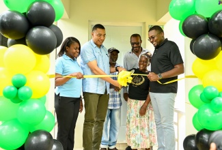 Prime Minister, the Most Hon. Andrew Holness (second left), leads a ribbon cutting exercise for a new two-bedroom unit under the New Social Housing Programme in North Central Clarendon, while Minister without Portfolio in the Ministry of Economic Growth and Job Creation (MEGJC) and Member of Parliament for the constituency, Hon. Robert Morgan (right); Permanent Secretary in the MEGJC, Arlene Williams (left); and Councillor, Chapelton Division, Hershell Brown (third right), look on. The proud beneficiaries are Pholando Clayton (third left) and his wife, Beverly. The dwelling was handed over on August 2.