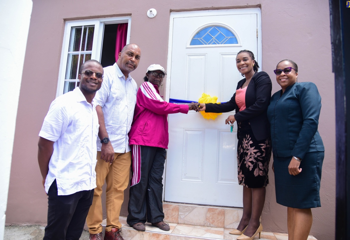 Managing Director of the HEART/NSTA Trust, Dr. Taneisha Ingleton (second right), assists homeowner Madge Shields (third left) in cutting the ribbon to her newly renovated home, at the handover ceremony on August 8 at Woodford Park in Kingston. Sharing in the moment (from left) are Councillor for the Trafalgar Division, Jesse James; Member of Parliament for St. Andrew South East, Julian Robinson; and Deputy Managing Director, HEART/NSTA Trust, Dr. Cheryl McLaughlin.

