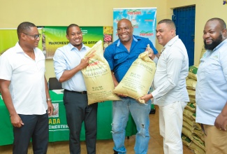 Minister of Agriculture, Fisheries and Mining, Hon. Floyd Green (second left), presents two bags of fertiliser to Manchester farmer, Peter Stevenson
(centre), who was impacted during the passage of Hurricane Beryl. The presentation was made during a ceremony at the National Irrigation Commission’s (NIC) Newport/Duff House Office in Manchester on Wednesday (July 31). The fertiliser was part of a batch donated by Newport Fersan Jamaica Limited in support of the Government’s post-hurricane recovery efforts. Assisting with the presentation (from left) are: Vice Chair, Rural Agricultural Development Authority (RADA) Manchester Parish Advisory Board, Damion Young; Manchester Southern Member of Parliament, Robert Chin; and Newport Fersan Sales Manager, Denton Alvaranga.
