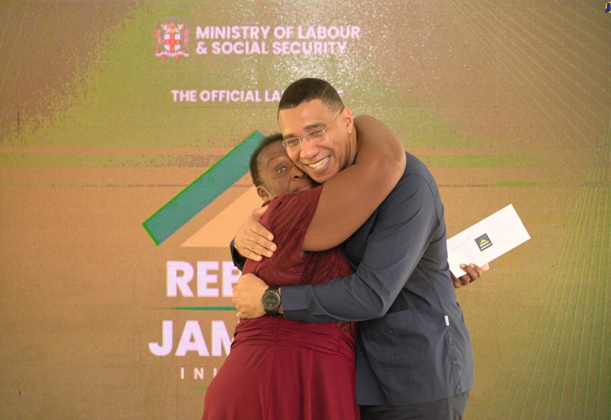 Prime Minister, the Most Hon. Andrew Holness, embraces grant recipient, Pauline Smith, of Grange Hill in Westmoreland, at the launch of the Rebuild Jamaica Initiative, held at the Ministry of Labour and Social Security offices in Kington, on August 5.