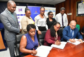 Permanent Secretary in the Ministry of Education and Youth, Dr. Kasan Troupe (seated centre); General Manager, Finance, Standards, Procurement, Jamaica Social Investment Fund, Orville Hill (seated right), and Director, Build Rite Construction, Chantay Campbell (seated left), affix their signatures to documents for expansion and rehabilitation works at the Mount Moriah Primary School in St. Ann,  at the Ministry’s Heroes Circle offices in Kingston on August 8. Observing from left are Member of Parliament St. Ann Southwestern, Hon. Zavia Mayne; Principal, Mount Moriah Primary School, Kerrol Lyons and other stakeholders.

