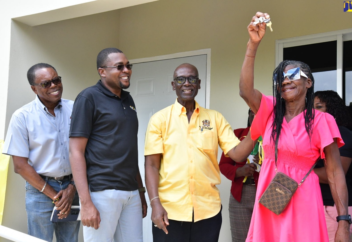 Minister of Local Government and Community Development, Hon. Desmond McKenzie (second right), and Minister without Portfolio in the Ministry of Economic Growth and Job Creation with Responsibility for Works and Member of Parliament for Clarendon North Central, Hon. Robert Morgan (second left), are all smiles as Marlene Stewart (right) of Pennants in the constituency displays the keys to her brand-new two-bedroom home, which was built under the Indigent Housing Programme. Also observing is Mayor of May Pen, Councillor Joel Williams. Ms. Stewart received the unit on Tuesday (August 20).

