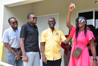 Minister of Local Government and Community Development, Hon. Desmond McKenzie (second right), and Minister without Portfolio in the Ministry of Economic Growth and Job Creation with Responsibility for Works and Member of Parliament for Clarendon North Central, Hon. Robert Morgan (second left), are all smiles as Marlene Stewart (right) of Pennants in the constituency displays the keys to her brand-new two-bedroom home, which was built under the Indigent Housing Programme. Also observing is Mayor of May Pen, Councillor Joel Williams. Ms. Stewart received the unit on Tuesday (August 20).

