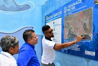 Minister without Portfolio in the Ministry of Economic Growth and Job Creation, Senator the Hon. Matthew Samuda (centre), and Consultant for the Kingston Cleanup Project, Deika Morrison (left), are shown the layout of the drainage network for the Kingston Harbour by Managing Director, Clean Harbours Jamaica Limited, Michael McCarthy. The occasion was a tour of interceptor barriers at Barnes Gully, along Port Royal Street in downtown Kingston on Thursday (August 22).

