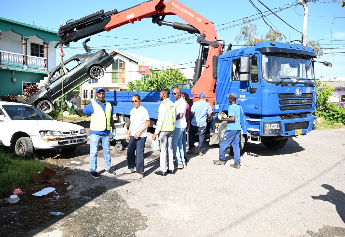 Executive Director of the NSWMA, Audley Gordon (left), in discussion with Minister of Legal and Constitutional Affairs and Member of Parliament for St. James West Central, Hon. Marlene Malahoo Forte (second left), as the entity removes a derelict vehicle from a section of Catherine Hall, during the launch of the Bulky Waste and Derelict Vehicle Removal Programme in St. James on Thursday, August 8. Also at the site are (from third left) Mayor of Montego Bay and Chairman of the St. James Municipal Corporation, Councillor Richard Vernon; Regional Operations Manager of WPM Waste Management Limited, Edward Muir,  and other NSWMA personnel

