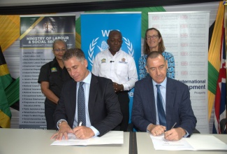 Minister of Labour and Social Security, Hon. Pearnel Charles Jr. (centre), Permanent Secretary in the Ministry, Colette Roberts Risden (left), and British High Commissioner to Jamaica, Her Excellency Judith Slater, observe as Head of the World Food Programme (WFP) Caribbean Multi-Country Jamaica Office, Dana Sacchetti (left, seated), and the United Kingdom (UK) Government’s Development Representative for Jamaica, Oliver Blake, sign a Memorandum of Understanding (MOU) for a cash grant initiative to benefit Hurricane Beryl victims. The signing took place at the Ministry in downtown Kingston on Tuesday (August 27).

