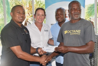 Minister of Agriculture, Fisheries and Mining, Hon. Floyd Green (left), presents a cheque, valued $25,000, to net fisher George Daley (right), during a presentation ceremony at the Caribbean Coastal Area Management (C-CAM) Foundation Field Station in Salt River, Clarendon, on Thursday (August 22). Sharing the moment are (from left) Executive Director, Sandals Foundation, Heidi Clarke; and Minister of Labour and Social Security and Member of Parliament for Clarendon South Eastern, Hon. Pearnel Charles Jr.

